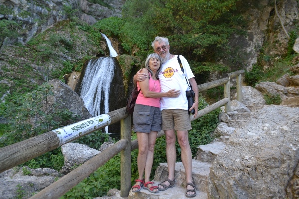 the traveling couple next to the two stretches of the main waterfall